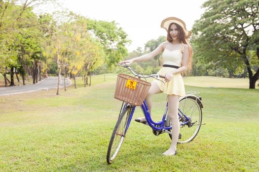 Asian woman riding a bicycle On the grass in the park. Woman wear long hair