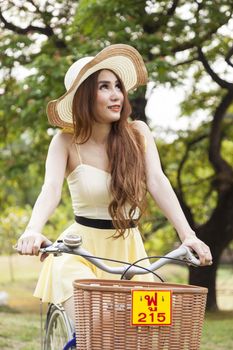 Woman riding a bicycle. Woman with hat riding a bicycle in the park.