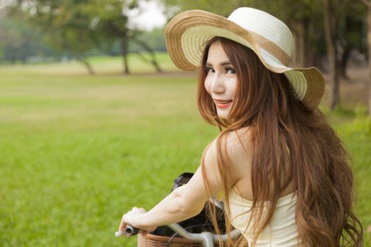 Woman riding a bicycle. Woman with hat riding a bicycle in the park.