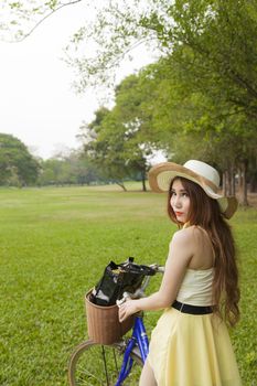 Woman riding a bicycle. Woman with hat riding a bicycle in the park.