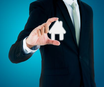 Businessman standing posture hand holding house icon isolated on over blue background