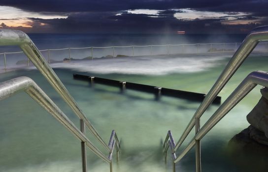 Bronte Baths, the ocean pool at Bronte Beach Sydney.  Waves surge into the pool constantly.  Focus is to the hand rails.  Buyers this is a long 8 sec exposure taken 1 hr before sunrise at 500 iso,  there may be some grain as I did not want to overuse noise reduction software