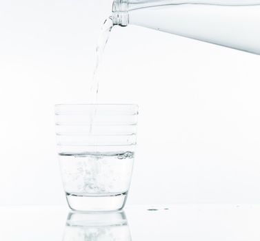 Pouring water on glass on over white background