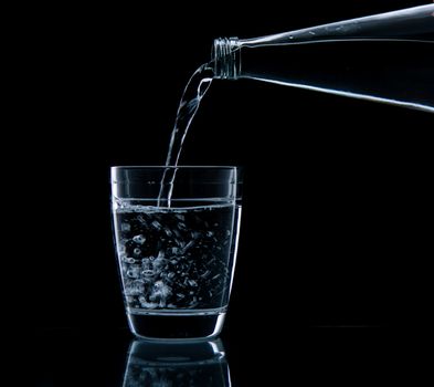 Pouring water on glass on over black background