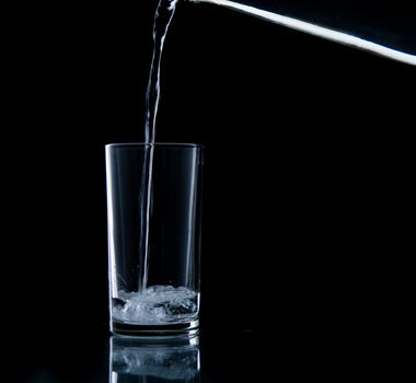 Pouring water on glass on over black background