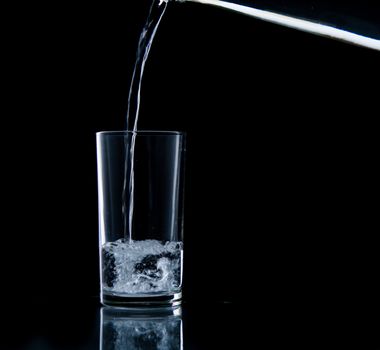 Pouring water on glass on over black background