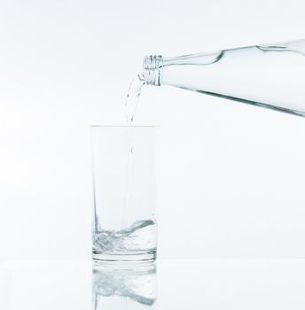 Pouring water on glass on over white background