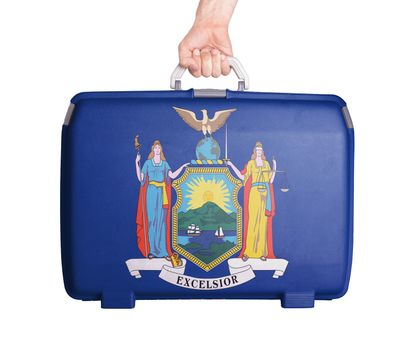 Used plastic suitcase with stains and scratches, printed with flag, New York