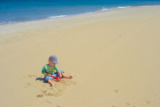 Little boy playing with sand on the beach