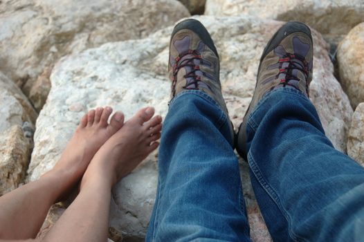 man and woman feet with natural beach rock as background