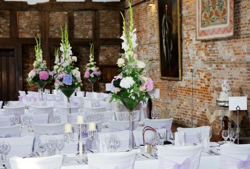 Wedding reception setting showing flower arrangements on table and purple chair covers