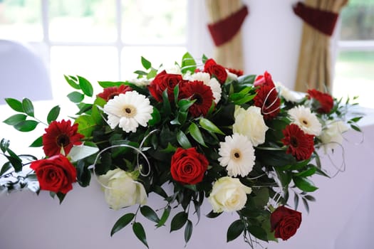 Red roses decorate table at wedding.