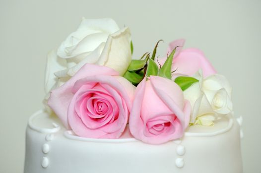 Pink and white roses decorate top of wedding cake.
