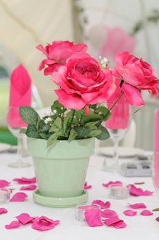 Pink roses decorate a table at wedding reception.