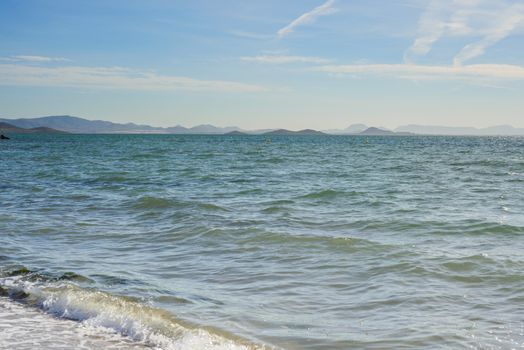 Mar Menor sea with waves, blue sky and mountains