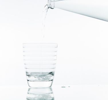 Pouring water on glass on over white background