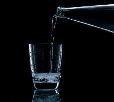 Pouring water on glass on over black background