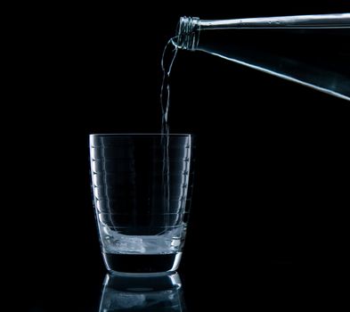 Pouring water on glass on over black background