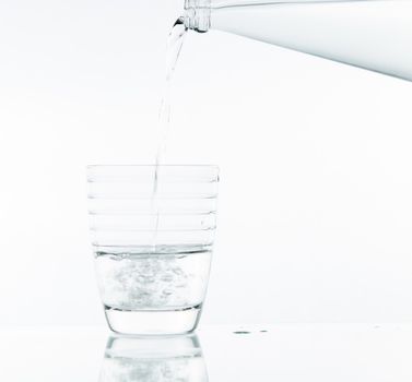 Pouring water on glass on over white background