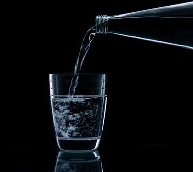 Pouring water on glass on over black background