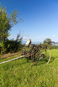 old unused agricultural machine standind on green grass