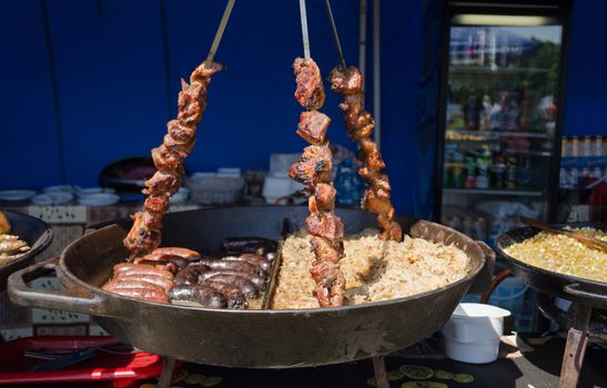 big bowl of rice sausage and three switches placed with shashlik on rural fair stall