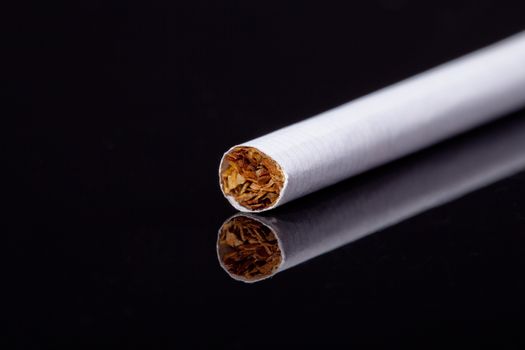 single thin cigarette isolated on black background macro
