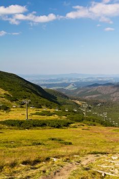 view on mountains in summer with ski lift on blue sky background