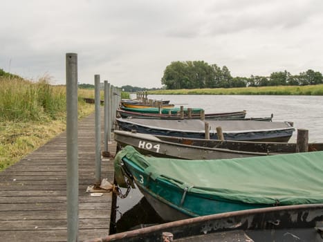 Row of covered boats along the Ijssel river in Doesburg, Netherlands. Cloudy and calm day