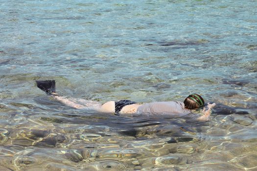 Woman photographer diving into water of Red sea