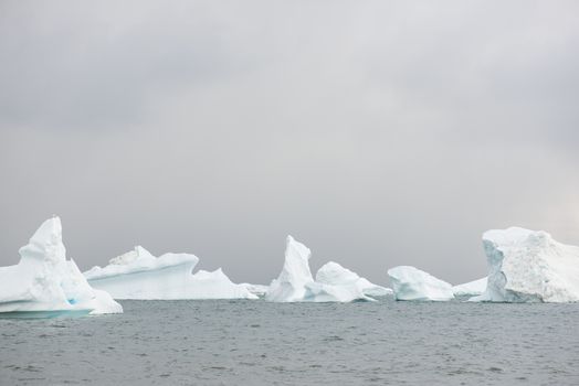 Beautiful icebergs in the sun and in front of a dark sky