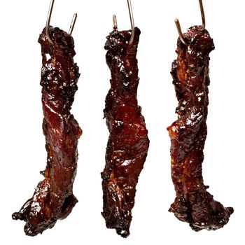 close up of chinese roasted char siu pork on hooks isolated