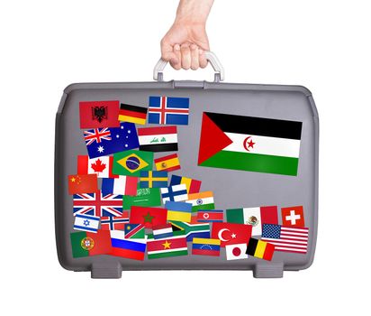 Used plastic suitcase with lots of small stickers, large sticker of Western Sahara