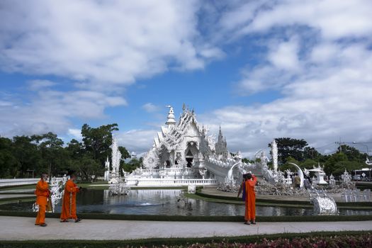 Buddhist Monks, White Temple and Modern Gadgets  Contemporary unconventional Buddhist temple  Editorial  Chiang Rai, Thailand -  July 10, 2014