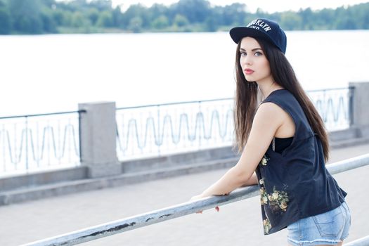 Street, outdoor. Attractive teen in a cap