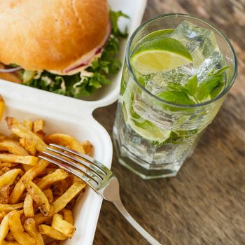 Fastfood, unhealthy. Tasty burger with fries on the table