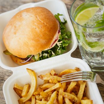 Fastfood, unhealthy. Tasty burger with fries on the table