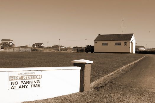 Ballybunion fire station with fire truck parked outside in sepia