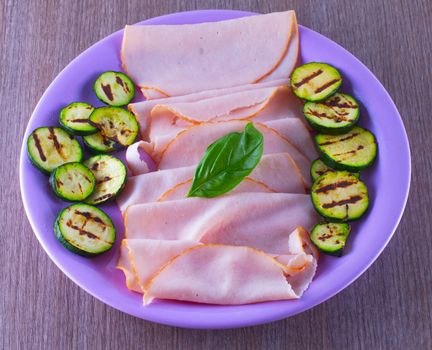 Turkey ham with grilled zucchini in a purple plate
