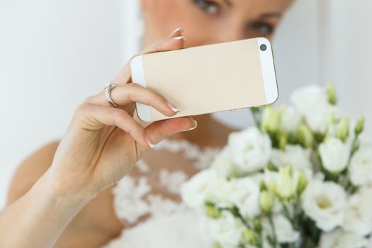 Wedding. Attractive bride with beautiful bouquet and mobile phone