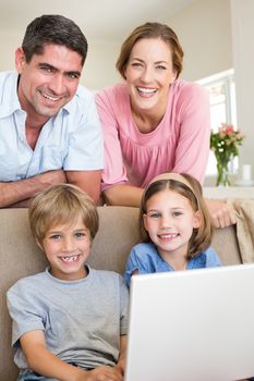 Portrait of happy family with laptop in living room
