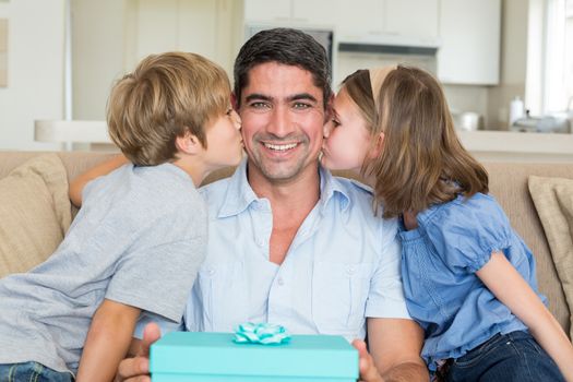 Loving children kissing on fathers cheeks at home