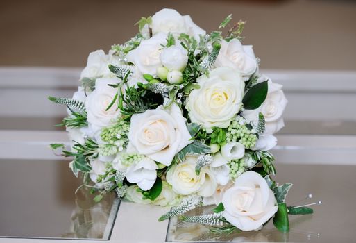 Close-up of brides flowers and grooms single rose on wedding day