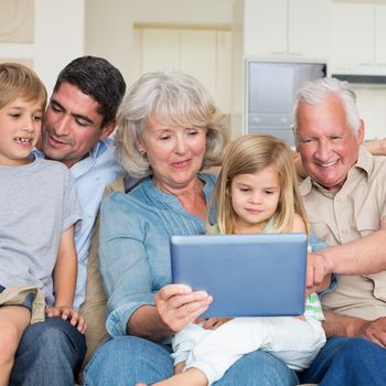 Smiling multigeneration family using digital tablet at home