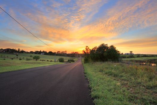 Country road, farms and paddocks at sunrise morning.  Focus to foreground