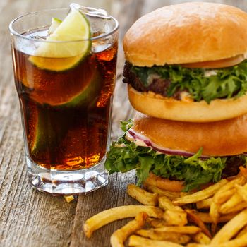 Fastfood, unhealthy. Tasty burgers with fries on the table