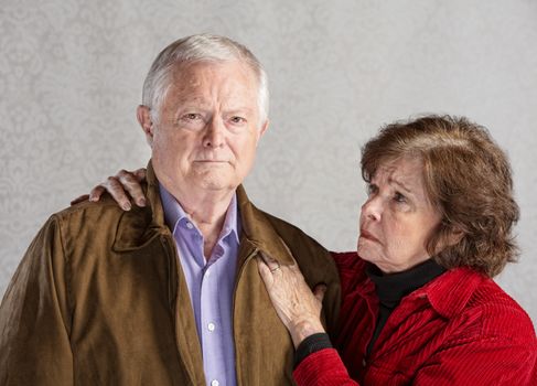 Concerned senior husband and wife over gray background