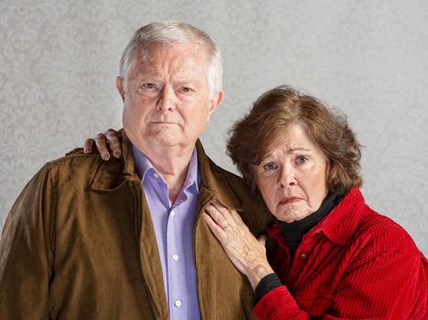 Serious Cauccasian older couple over gray background