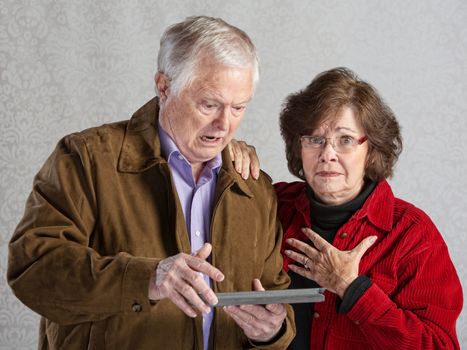Angry man using tablet with embarrassed woman