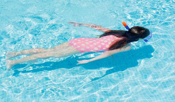 Young girl snorkeling in a clear pool 